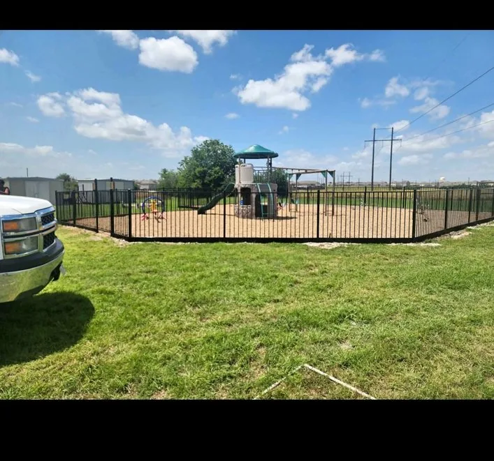 Black ornamental perimeter fence surrounding a playground